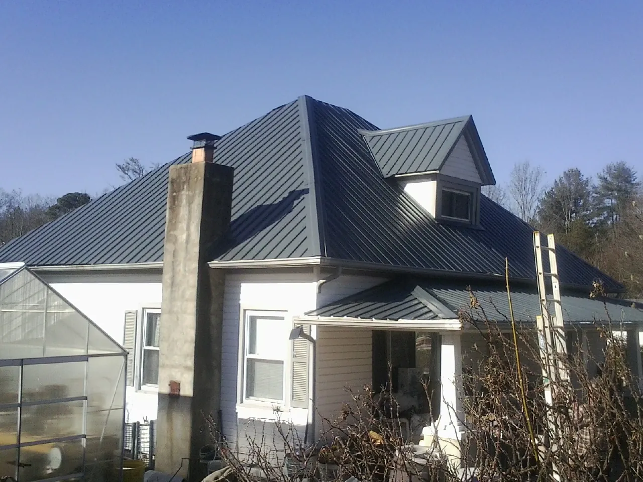Dark blue standing seam metal roof on a white farmhouse with dormer — Slate & Tile Roof Repair by Roofing Brothers in Ware Shoals