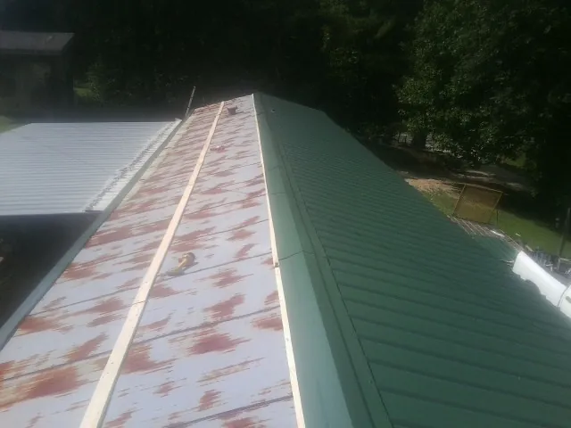 Old rusted panels beside newly installed green metal roofing — Wind Damage Roof Repair by Roofing Brothers in Ware Shoals