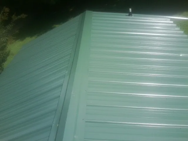 New green metal panels meeting at the ridge of a roof — Flat Roof Repair work by our crew in Ware Shoals