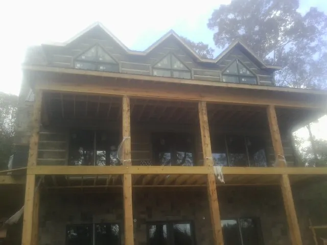 Dormers and porch framing on a large log home under construction — Roof Coating work by our crew in Ware Shoals