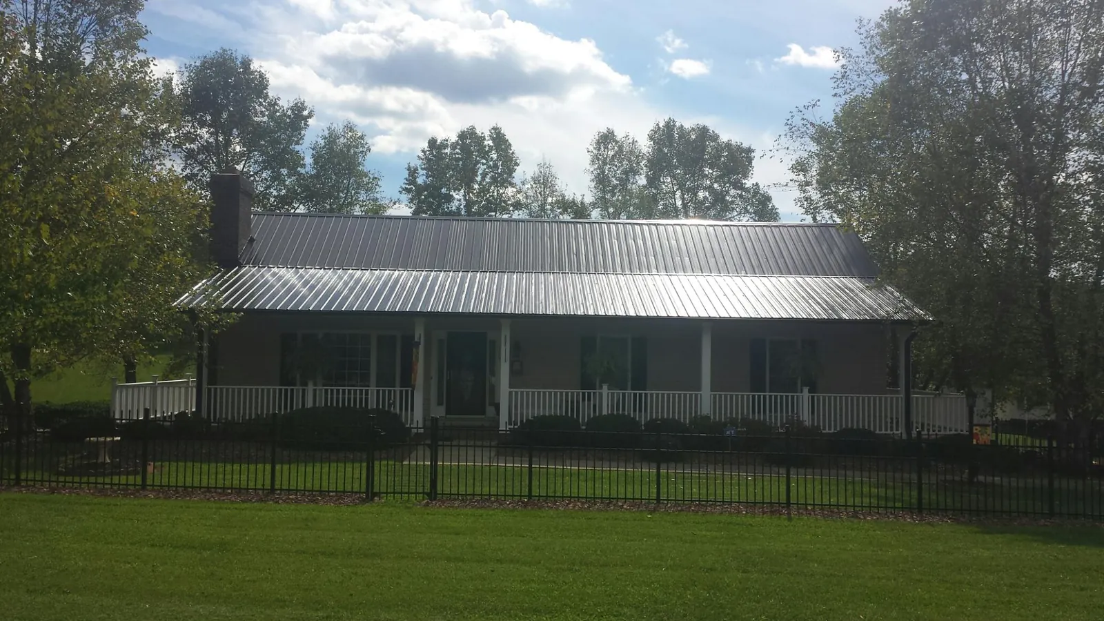 Gray metal roof on a brick ranch with a full width front porch — Gutter Guard Installation work by our crew in Ware Shoals