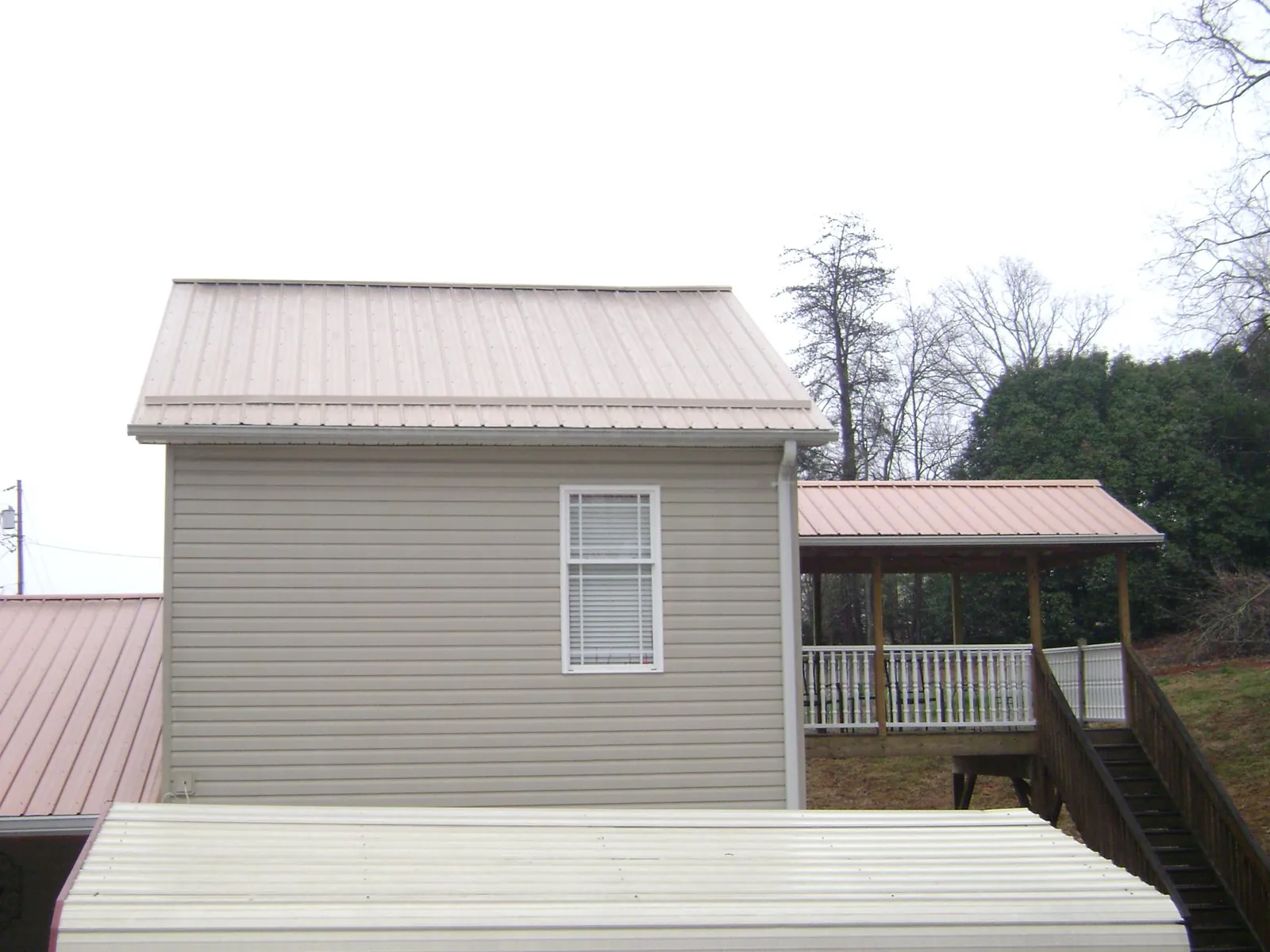 Tan metal roofs on a two story addition and attached porch, from a Roof Replacement job in Ware Shoals