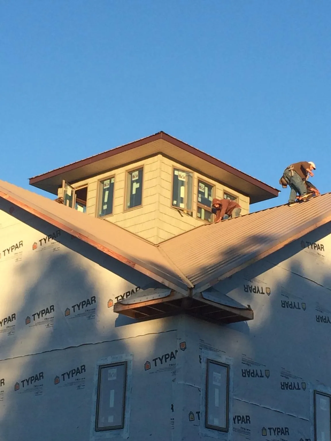 Roofers working around a rooftop cupola on a new metal roof at sunset — Roof Waterproofing in Ware Shoals by Roofing Brothers